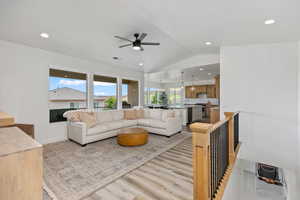 Living area with vaulted ceiling, light wood-style flooring, recessed lighting, a chandelier, and ceiling fan