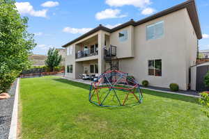Rear view of property with a trampoline, stairs, stucco siding, and a yard