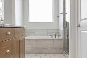 Full bath featuring vanity, a bath, a shower with door, and light tile patterned flooring