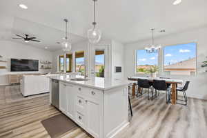 Kitchen featuring white cabinetry, recessed lighting, pendant lighting, vaulted ceiling, and a kitchen island with sink