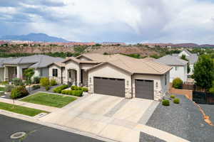 View of front of house with a mountain view, a garage, concrete driveway, and stone siding