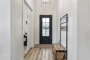 Entryway with wood finished floors and a chandelier