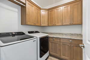 Laundry area with cabinet space, independent washer and dryer, and light wood finished floors