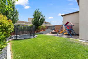 Fenced backyard with a trampoline and a playground