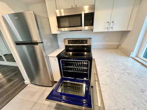 Kitchen featuring appliances with stainless steel finishes, light countertops, white cabinetry, and light tile patterned floors