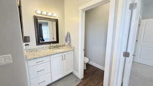 Bathroom with vanity, toilet, wood finished floors, and baseboards