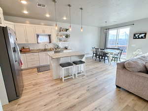 Kitchen featuring appliances with stainless steel finishes, a textured ceiling, white cabinets, light stone countertops, and a kitchen island