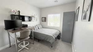 Carpeted bedroom with baseboards and a desk