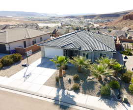 View of front of property with a garage, concrete driveway, a tiled roof, a residential view, and a mountain view