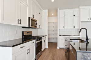 Kitchen featuring appliances with stainless steel finishes, a sink, recessed lighting, light wood-style floors, and tasteful backsplash