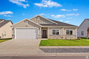 Craftsman-style house with board and batten siding, stone siding, a garage, and concrete driveway