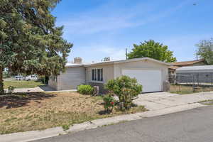 Ranch-style house featuring a garage, concrete driveway, and a chimney