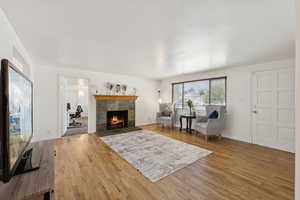 Living room featuring a tiled fireplace, wood finished floors, and baseboards