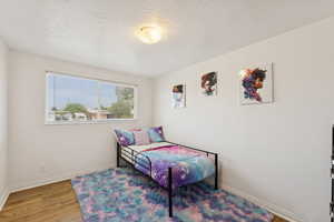 Bedroom featuring a textured ceiling, wood finished floors, and baseboards