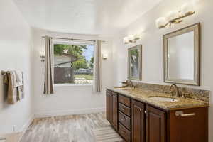 Bathroom with wood finished floors, double vanity, and baseboards