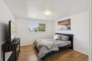 Bedroom with baseboards, wood finished floors, and a textured ceiling