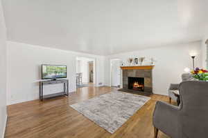 Living area with a fireplace, wood finished floors, and baseboards