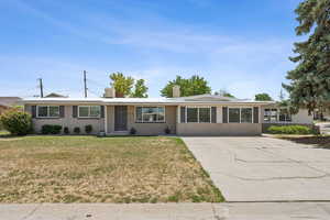 Single story home featuring a chimney, a front lawn, concrete driveway, and brick siding