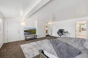 Carpeted bedroom with multiple windows, beamed ceiling, baseboards, and connected bathroom