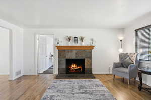 Living area with a tile fireplace, wood finished floors, and baseboards