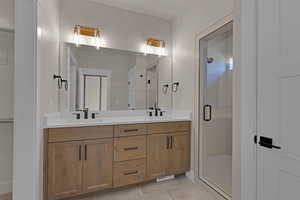 Full bath with double vanity, a shower stall, and tile patterned flooring