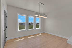 Unfurnished dining area with light wood-style flooring and baseboards