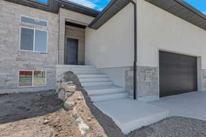 View of home's exterior featuring stone siding, a garage, and driveway
