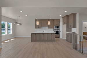 Kitchen featuring stainless steel appliances, light countertops, baseboards, light wood finished floors, and recessed lighting