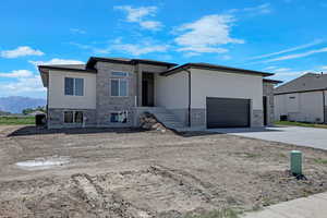 Prairie-style house featuring stone siding, driveway, an attached garage, and a mountain view