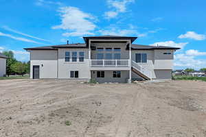 Back of house with stucco siding and stairs