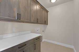 Washroom with hookup for an electric dryer, cabinet space, hookup for a washing machine, baseboards, and light tile patterned floors
