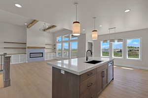 Kitchen with a sink, stainless steel dishwasher, open floor plan, beamed ceiling, and light countertops