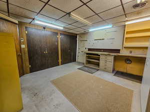 Finished below grade area with a workshop area, a drop ceiling, and wooden walls