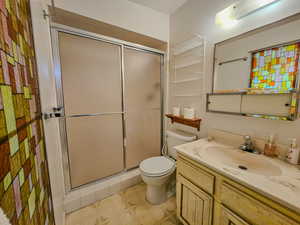 Bathroom with a shower stall, toilet, vanity, and tile patterned floors