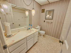 Bathroom featuring toilet, vanity, and baseboards