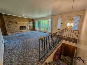 Living room featuring a chandelier, carpet flooring, track lighting, and a brick fireplace
