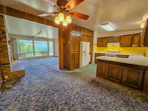 Kitchen featuring white appliances, a sink, carpet, under cabinet range hood, and ceiling fan
