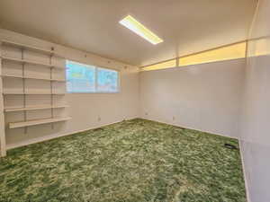 Empty room with vaulted ceiling and carpet flooring
