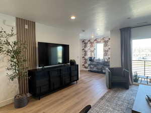 Living room with light wood finished floors, baseboards, wallpapered walls, and an accent wall
