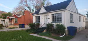 View of front of house with a shingled roof, stucco siding, and a front lawn