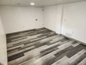 Spare room featuring dark wood-style flooring and baseboards