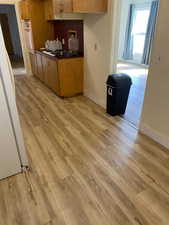 Kitchen with light wood-style flooring, baseboards, dark countertops, white appliances, and a desk