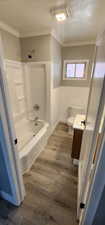 Full bathroom featuring a textured ceiling, toilet, vanity, ornamental molding, and washtub / shower combination