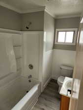 Full bath with toilet, vanity, wood finished floors, a textured ceiling, and tub / shower combination