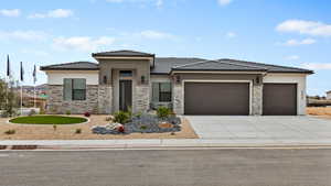 Prairie-style home with an attached garage, stone siding, driveway, and a tile roof