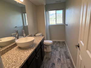 Full bath with vanity, wood finished floors, baseboards, toilet, and a shower with curtain