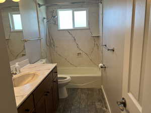 Bathroom featuring toilet, vanity, plenty of natural light, and tub / shower combination