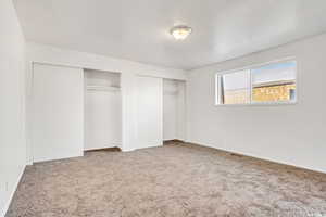 Unfurnished bedroom featuring multiple closets, carpet floors, and baseboards