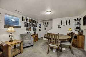 Dining room featuring a textured ceiling, light carpet, and stairs