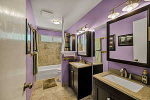 Bathroom featuring two vanities, toilet, and shower / tub combo with curtain